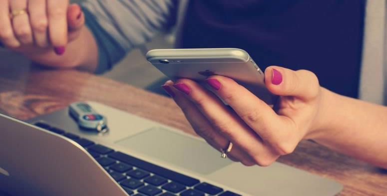 woman reading "12 Quotes to Make Customer Retention the Focus of Your Business" on laptop and iphone